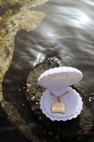 white shell of venus and a gold light necklace with mythology references